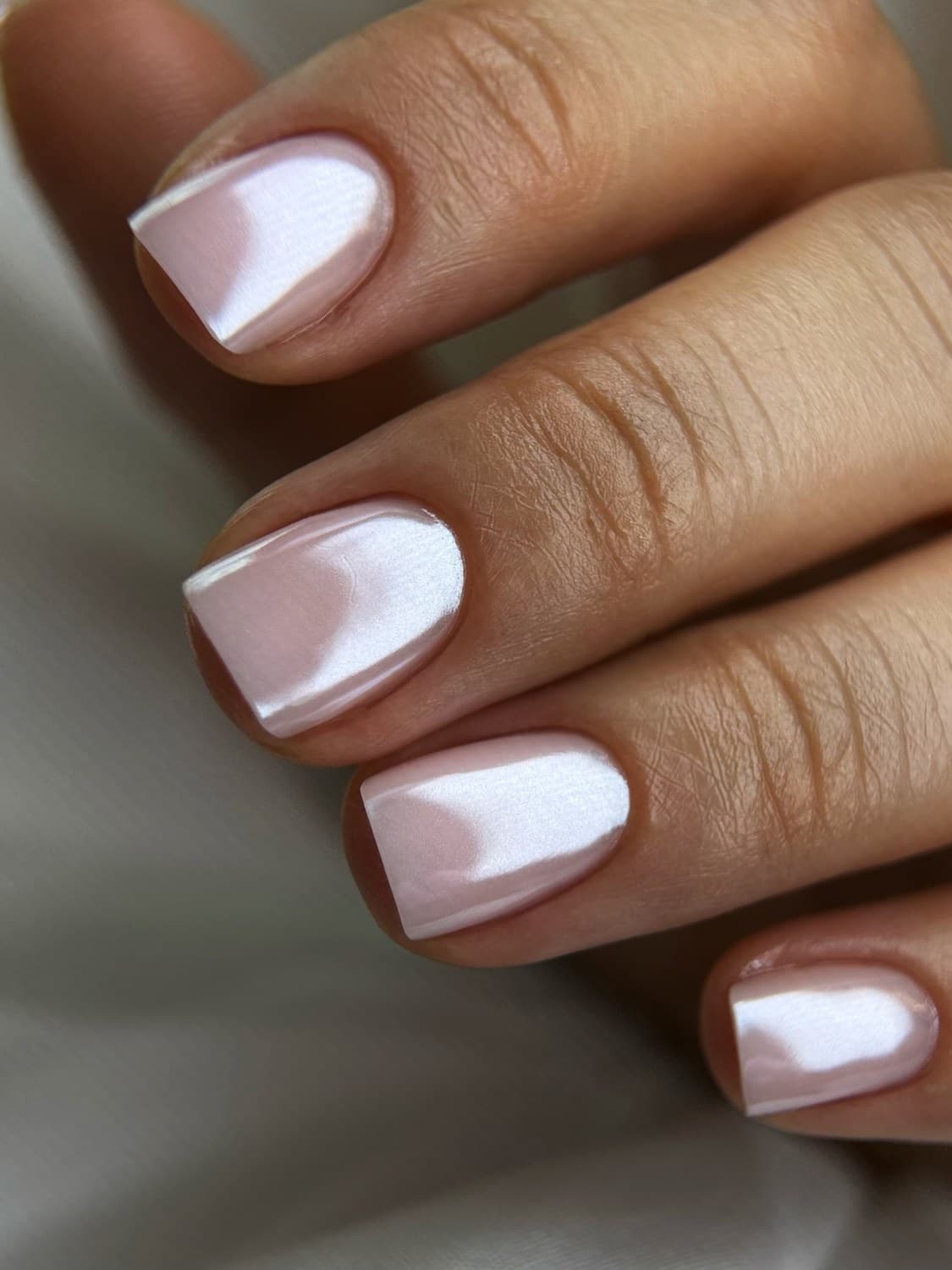 A pearl-white chrome manicure on clean, square-shaped nails